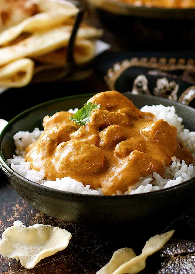 Image of Cooked Butter Chicken Over Steamed White Rice in a Bowl